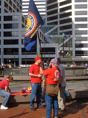Three guys in red t-shirts with an IBEW flag