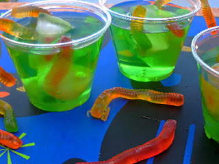 3 cups of green drink with gummy worms in them