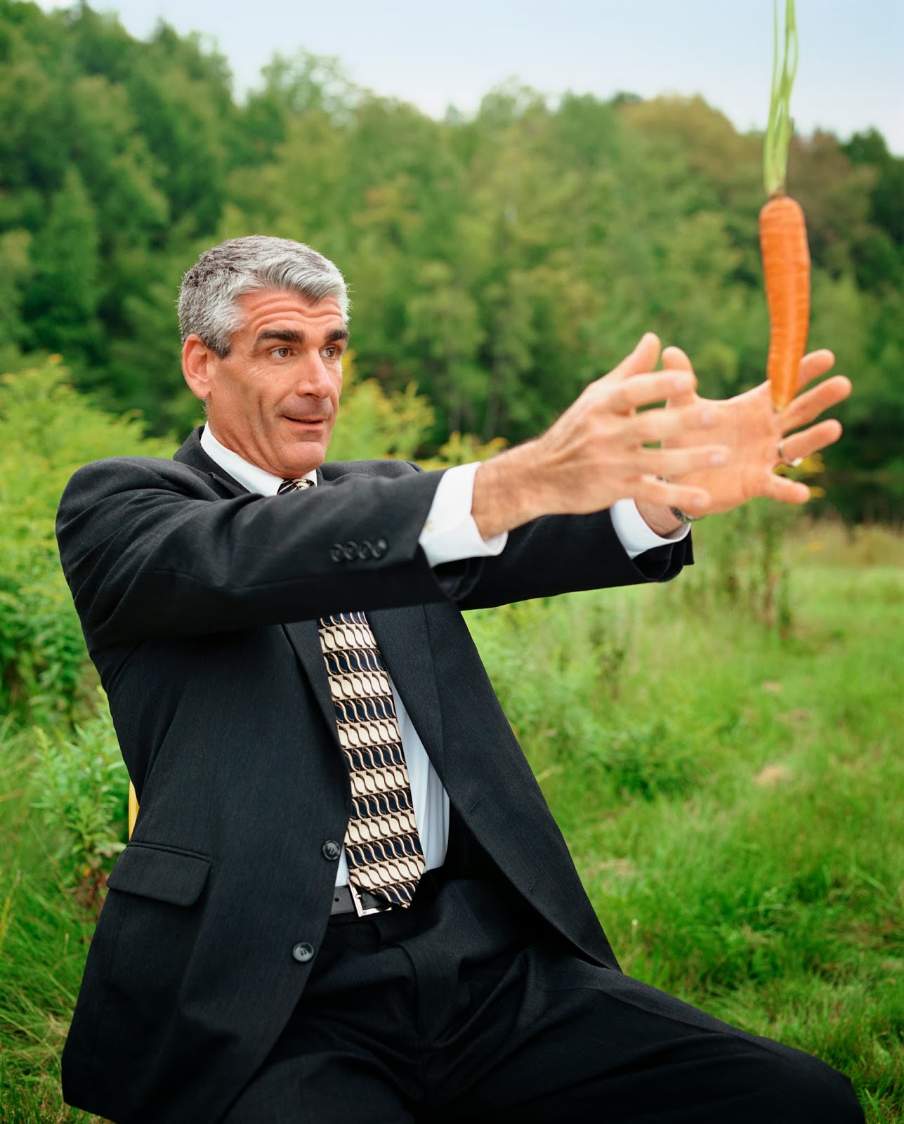 man in business suit reaching for carrot