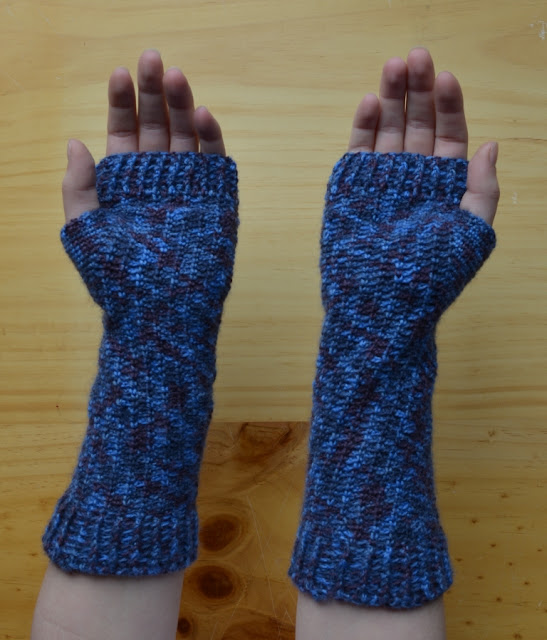 A pair of fingerless mitts with extra length at the wrist, extending two-thirds of the way up the forearm. This view is of upturned hands showing the palms of the mitts.