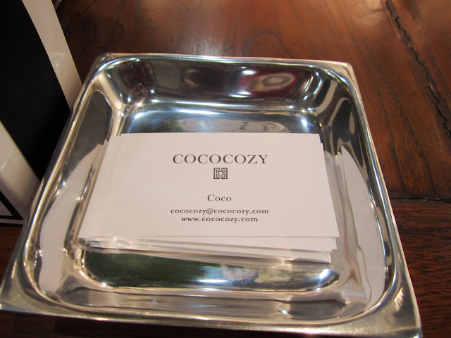 Coco's card in a silver dish on a wood table at the Nbaynadamas booth during the New York International Gift Fair