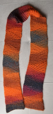 Vesuvius slip stitch scarf graduating colours of charcoal, deep pink reds, oranges, browns.