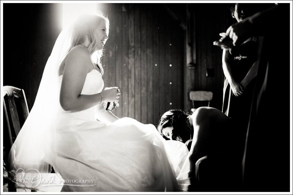 Helping hands Bridesmaid helps put on the bride's shoes.