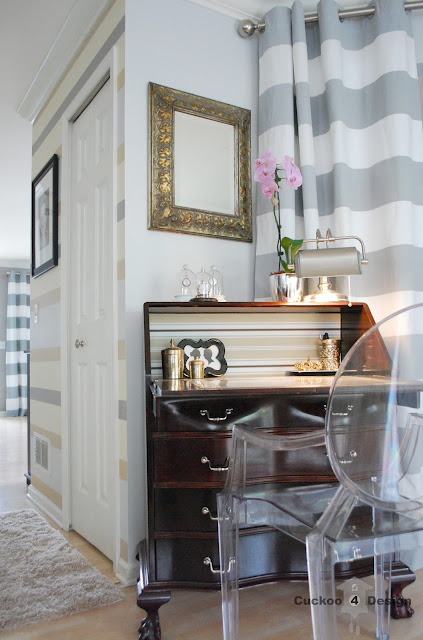 red mahogany stained secretary with claw feet and horizontal stripe curtains