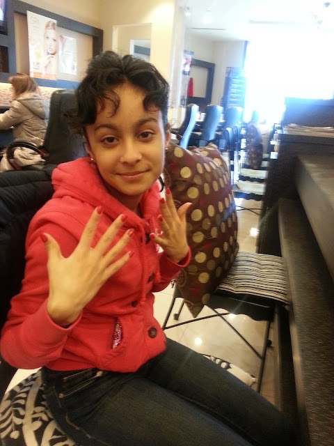 A teenager holding up her painted nails at a nail salon