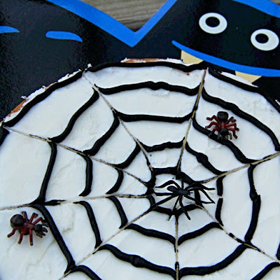 cookie decorated like a spider web with 3 plastic spiders on it