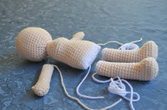 Doll pieces waiting to be joined together: head and torso, arms and legs.