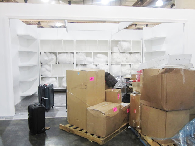 White lacquer display with floating shelves with boxes holding the rest of Nbaynadamas's booth for the New York International Gift Fair