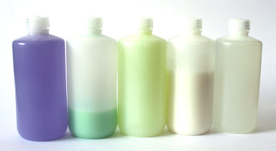 5 translucent plastic bottles filled with various colored liquids