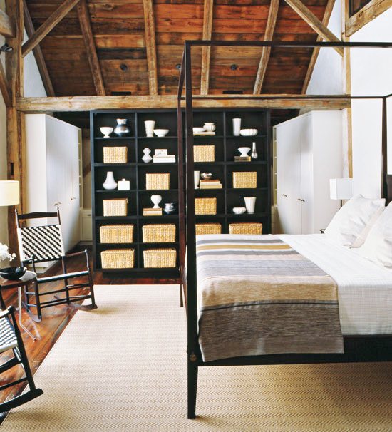 Bedroom with woven rocking chairs, canopy bed, open shelving with baskets, reclaimed wood floors and matching ceiling and exposed beams