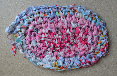 A partially completed oval-shaped crocheted rag rug.