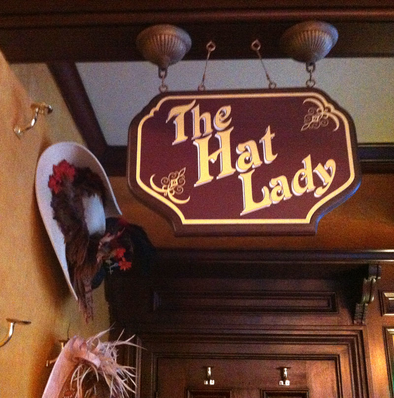 The Hat Lady sign hanging in the Rose & Crown pub, alongside her many hats