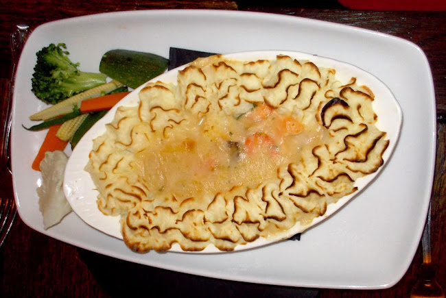 Crown Fish Pie-Smoked Haddock, Salmon and Prawns. Served in a white wine and cheese saude. Topped with mash and vegetables.