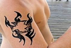 Black tribal ribbon tattoo on arm