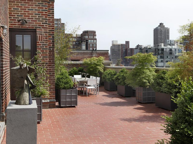 Outdoor terrace with brick floor, potted plants and a view of New York City
