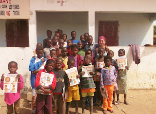 Lucy (top right) with village kids holding up their new Tostan children's books.