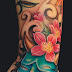 Sugary skull tattoo with pinkish flower tattoo on arm