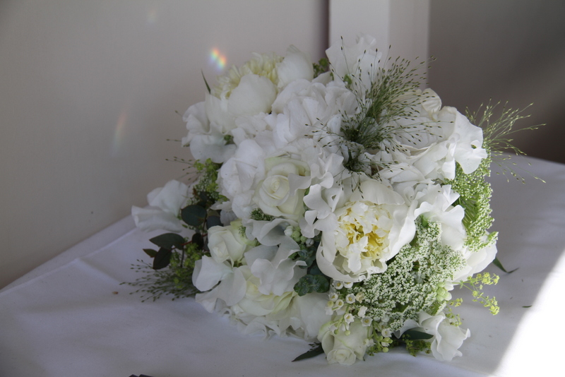 An all white Bridal Bouquet of Peonies Lily of the Valley Sweet Peas 