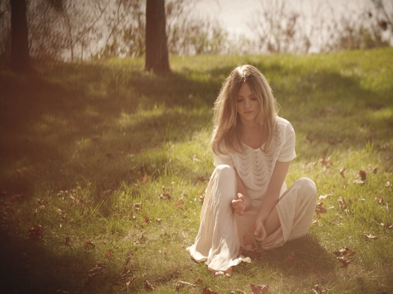 Белокурая фея с белой накидкой на плечах резвится в лесу