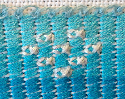 A school of white fish and detail of the coral stitch used for the waves
