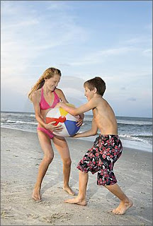 [maschio e femmina fanno la guerra dei sessi con la palla sulla spiaggia con le gambe nude in mutande]