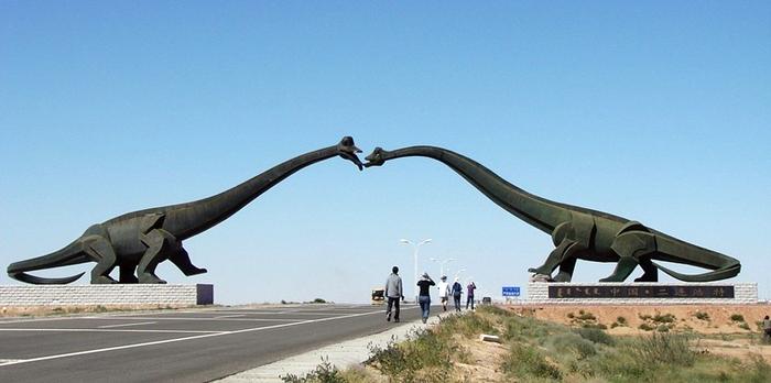 The Kissing Dinosaurs of Erenhot in China North of China on the Sino-Mongolian border, near the town of Erenhot (also known as Erlian), you will find the statues of two towering Brontosauruses. The two dinosaurs are located on either side of the main highway, their long necks stretching to the other, until the two dinosaur's mouth meet as if to share a kiss. Each dinosaur statue is 34 meters wide and 19 meters high. The span of the two together reaches 80 meters. The ground near the kissing couple is littered with many dozen smaller statues of dinosaurs of all shapes and sizes.