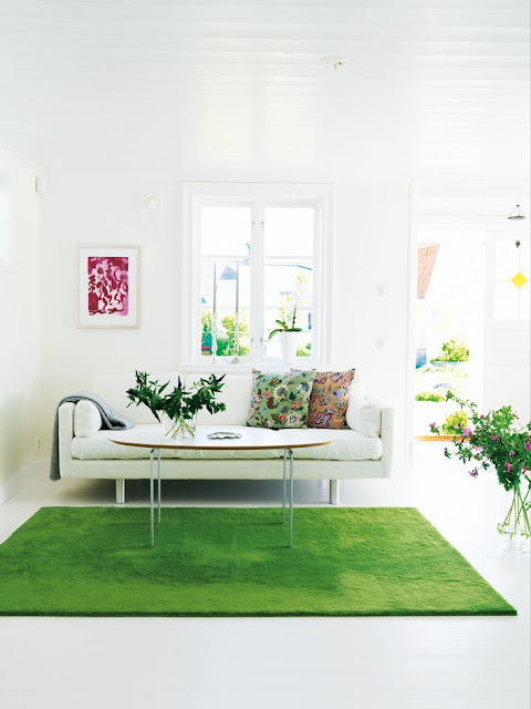 White living room with an oval coffee table and sofa with a grass green rug
