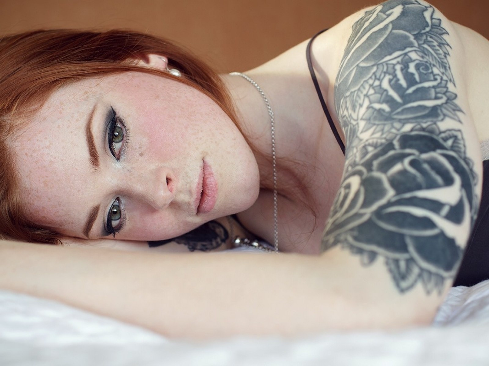 Фото рыжей женщины с яркими тату на светлой коже