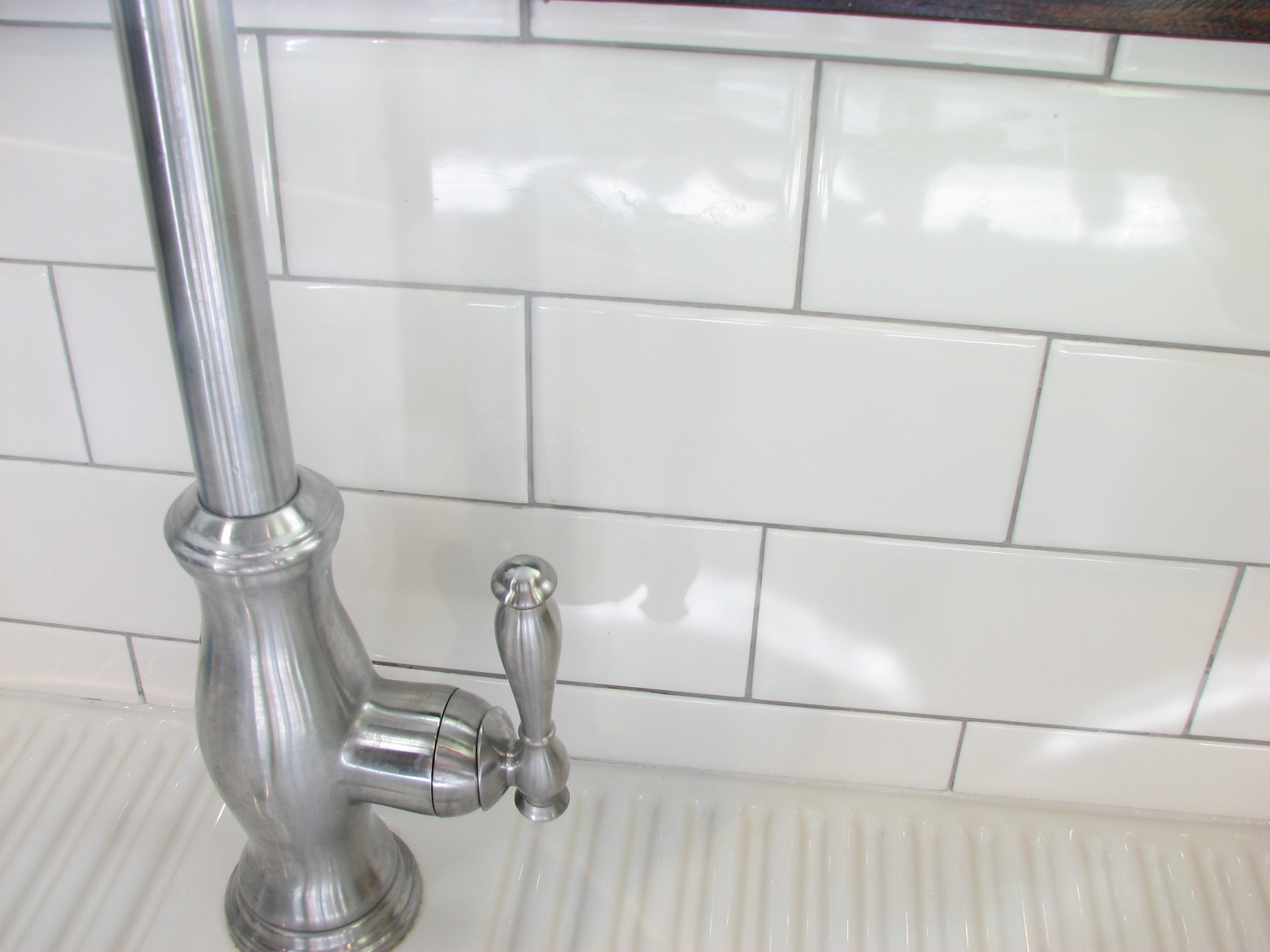 Subway tile with silver grout and white caulking along bottom