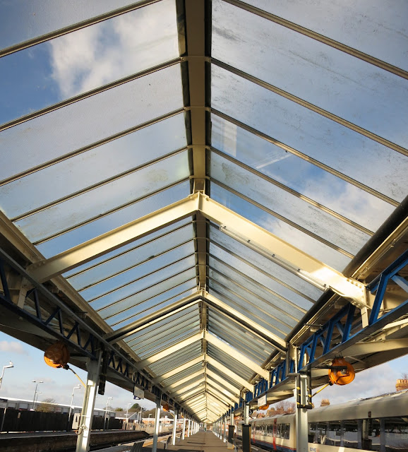 Seeing blue sky through glass roof at railway station.