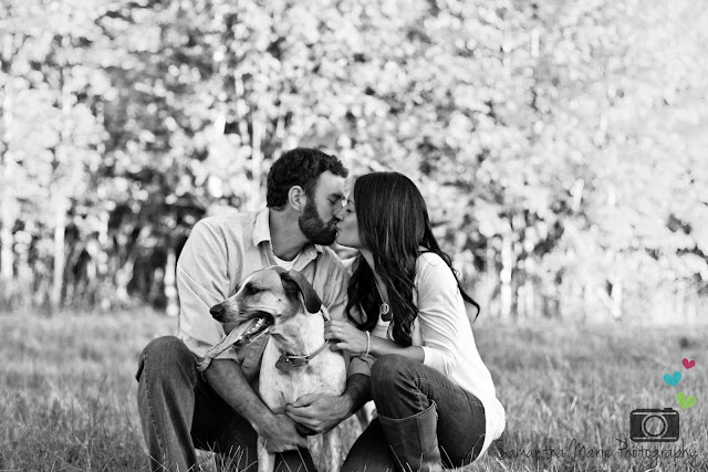 beautiful couple holding their dog while kissing