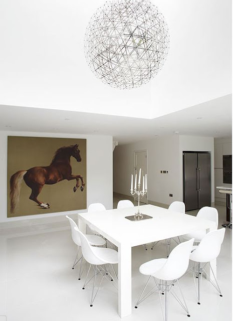 white Eames chairs surrounding a square white table in a white dining room with a large picture of a horse on one wall