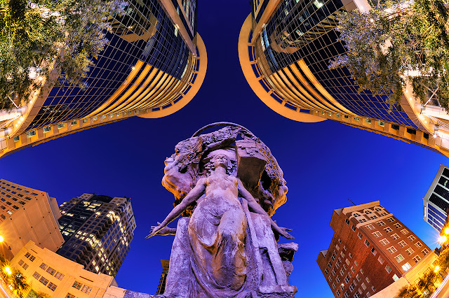 colorful statue of muses overlooking plaza theater at night