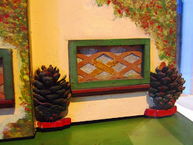 Close up of a vintage doll's house window, with trees in front of it, made of pine cones.