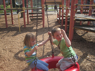 A totally different playground, a totally different day Two children on a tyre swing at a playground