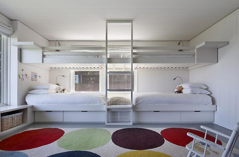 Kids bedroom in a lake house in Montauk on Long Island with two sets of white bunk beds with a ladder in between, a large poka dot rug and a white rocking chair