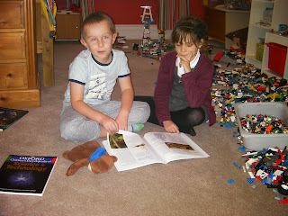 boy and girl reading with lego piles