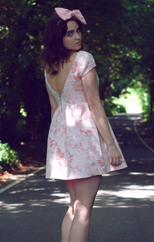 back view, looking over shoulder uk fashion style, dahlia fashion tapestry floral Jacquard dress styled with pink bow, vintage opal gold necklace, white platform wedges and a huge pink hair bow from roses and clementines, a tea party look, inspired by alice in wonderland, through the looking glass uk fashion style, dahlia fashion tapestry floral Jacquard dress styled with pink bow, vintage opal gold necklace, white platform wedges and a huge pink hair bow from roses and clementines, a tea party look, inspired by alice in wonderland, through the looking glass