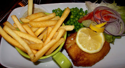Beer Battered Fish of the Day served with Fries peas and salad garnish.