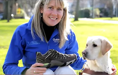 GDB Guide Dog Instructor Polly Dugan crouches next to a yellow Lab Guide Dog in his harness