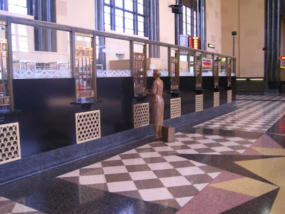 Ticket windows with metal grates. A sculpted woman figure stands at one window