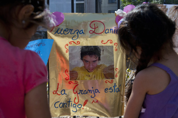 Duas meninas observam cartaz com foto de Daniel Samudio em portão de hospital em Santiago, nesta quinta (28); jovem de 24 anos morreu após ataque de neonazistas que o deixou 25 dias em coma (Foto: Claudio Santana / AFP)