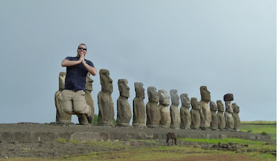 a man kneeling in front of a row of stone statues