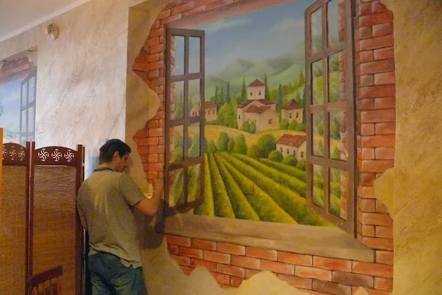 Malowanie obrazu na ścianie w pizzerii, obraz przedstawia widok z okna na winnicę
