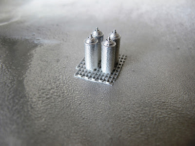 Four modern dolls' house miniature spray cans, painted silver.