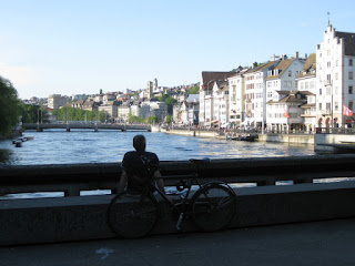 Cyclist relaxes in the evening shadows on a bridge over the Limmat in Zürich, Switzerland.