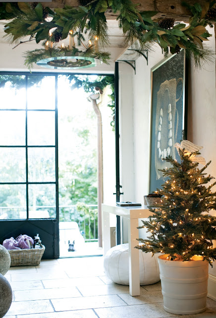 Foyer with small Christmas tree, white Moroccan pouf and a tile floor