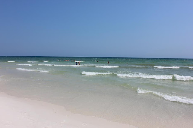 Ankle to shin high waves on Pensacola Beach at 18th. Ave with clear blue skies and tourists in the water