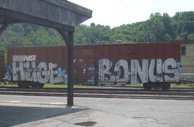 Graffiti words on a brown rail car reading HUGE BONUS
