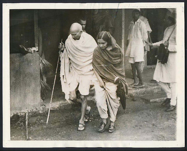 Mahatma+Gandhi+with+a+Bamboo+staff+strolling+through+a+village+with+assistance+by+a+woman+congress-worker+-+1942